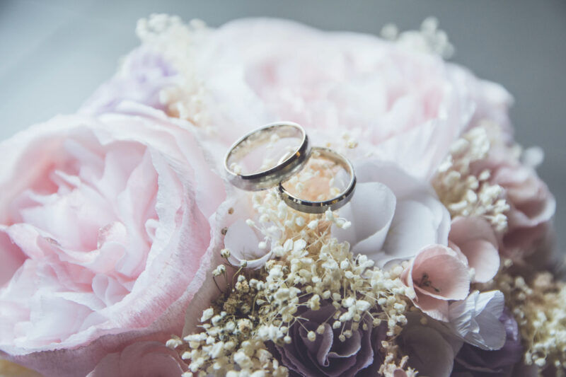 ピンクの花束に結婚指輪が載せられた写真