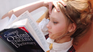 寝転がりながら読書をするブロンドヘアの少女