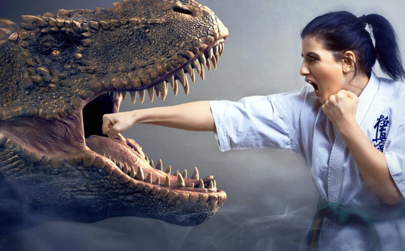 大きく口を開けた恐竜に正拳突きをする女性の画像